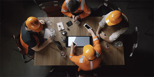 Construction team reviewing induction records on tablets and phones